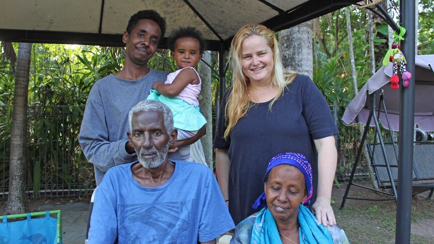 Three generations of a Somali family sits with their friend in a Darwin backyard.