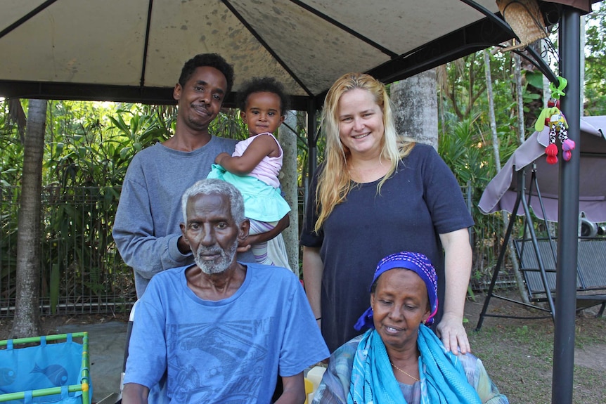 Three generations of a Somali family sits with their friend in a Darwin backyard.