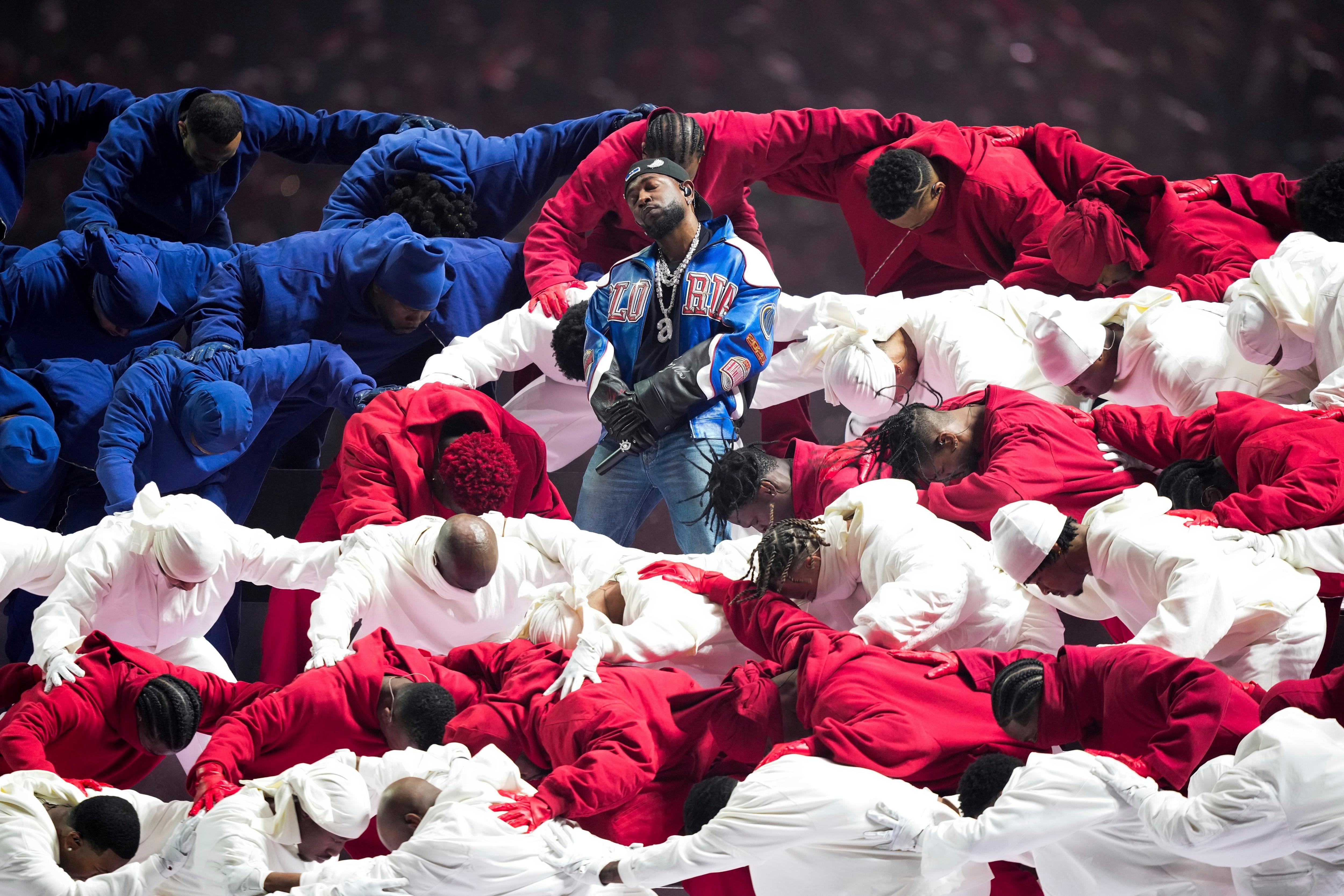 Artista entre dançarinos vestidos de vermelho, branco e azul durante o show do intervalo