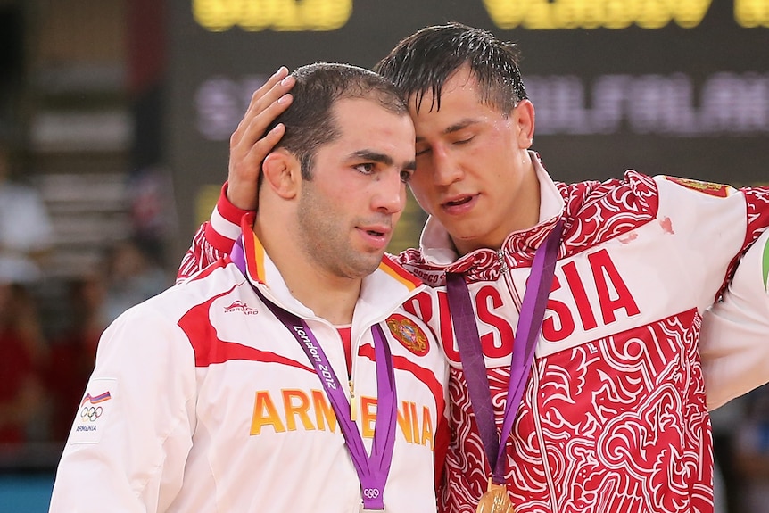 Silver medallist Arsen Julfalakyan is embraced by gold medallist Roman Vlasov on the wrestling podium at the London Olympics.