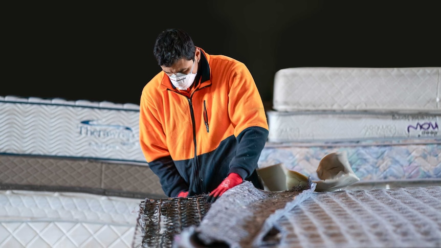 Worker in mask dismantles mattress