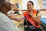 Health care worker Desleigh Shields listens to a patient's heartbeat.