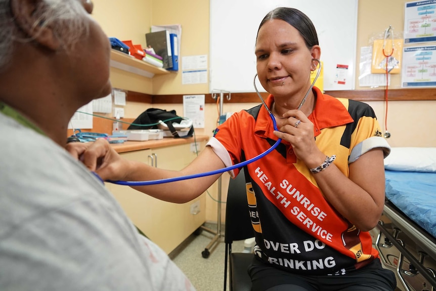 Health care worker Desleigh Shields listens to a patient's heartbeat.