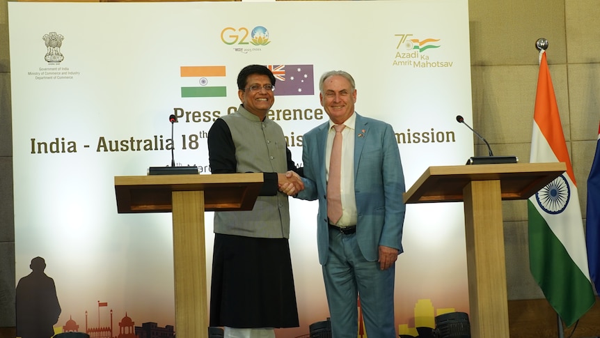 Two men shaking hands behind two lecterns 