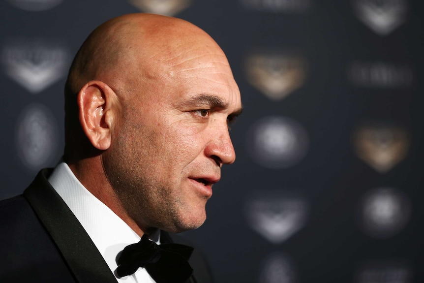 A former rugby league player dressed in a tuxedo, pictured in profile.