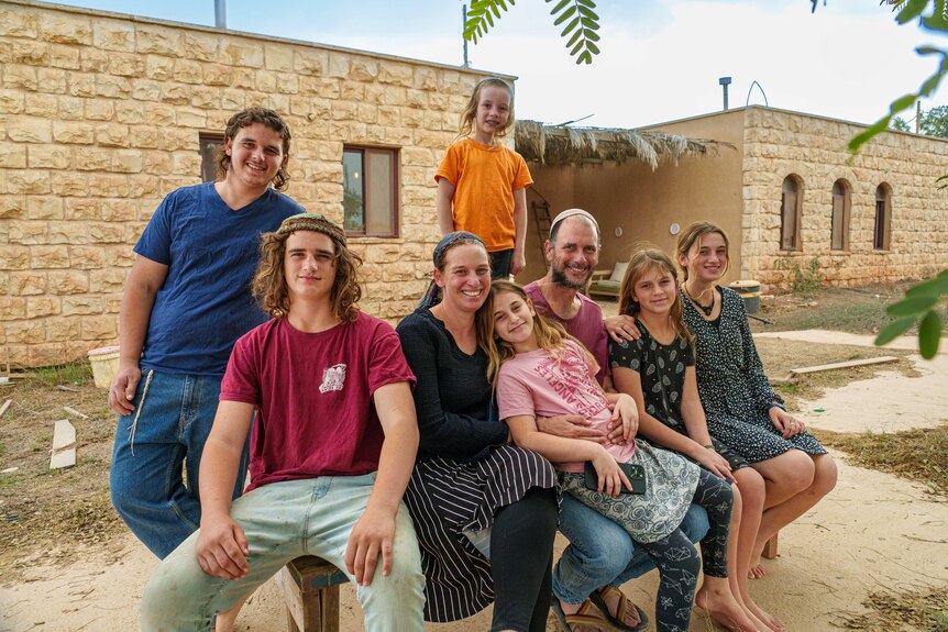 A family sits outside a stone house