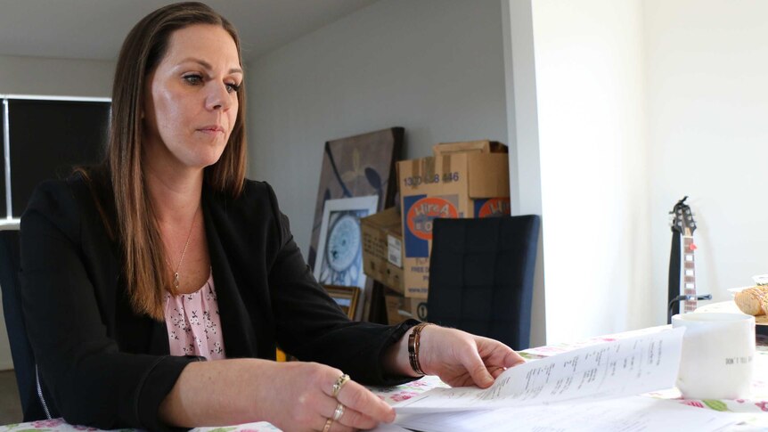 Amanda Dunn examines paperwork related to her late husband's insurance policy