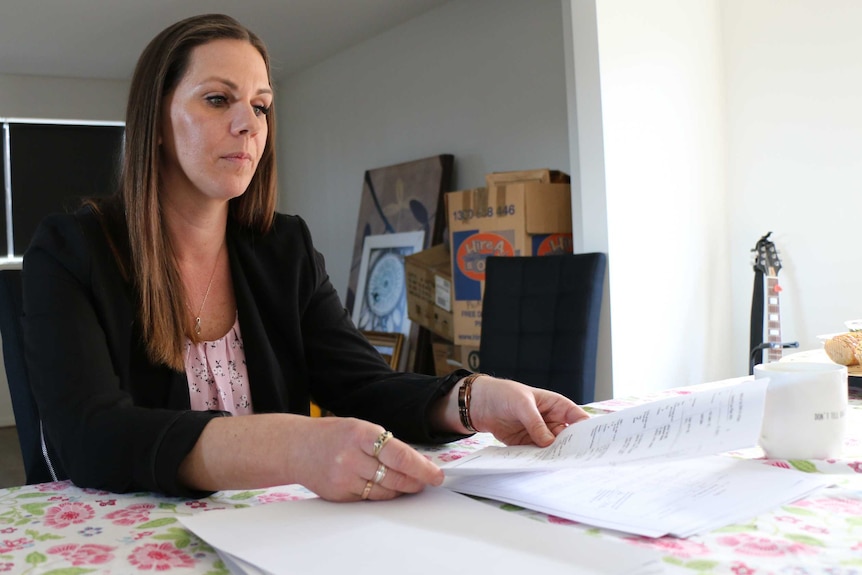 Amanda Dunn examines paperwork related to her late husband's insurance policy
