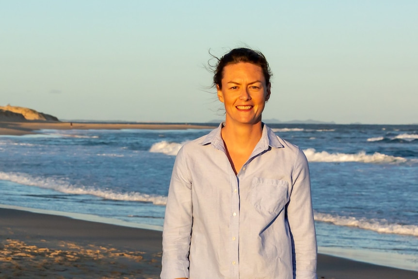 a woman stands in front of a beach in newcastle