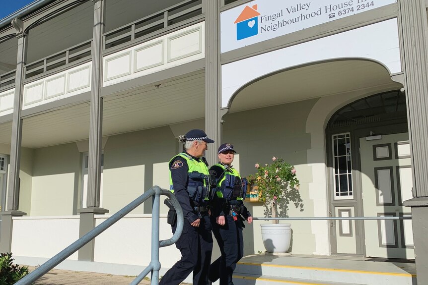 Two female police officers walk past a building