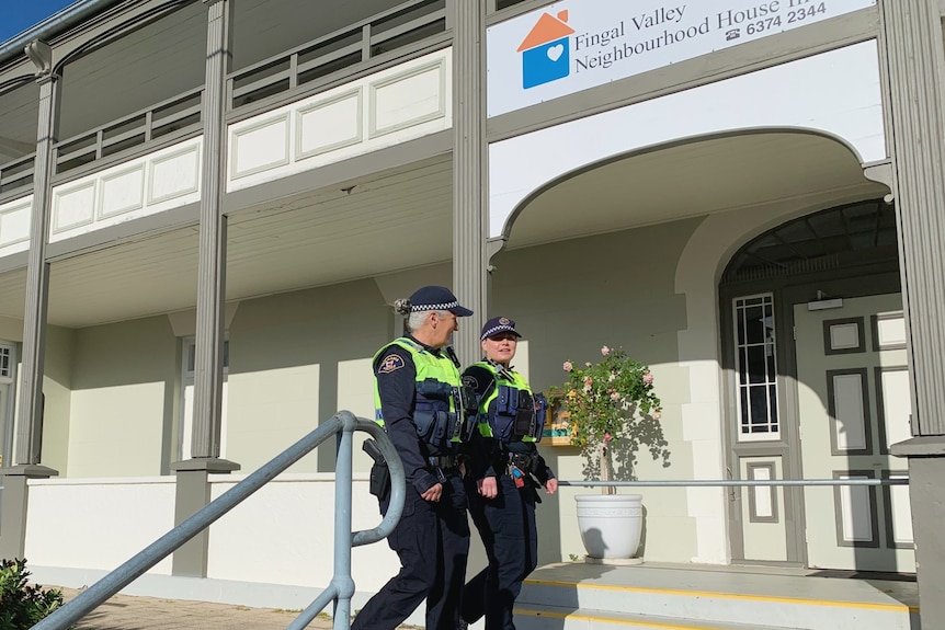 Two female police officers walk past a building