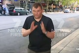 A man raises his hands, recreating pushing a trolley.