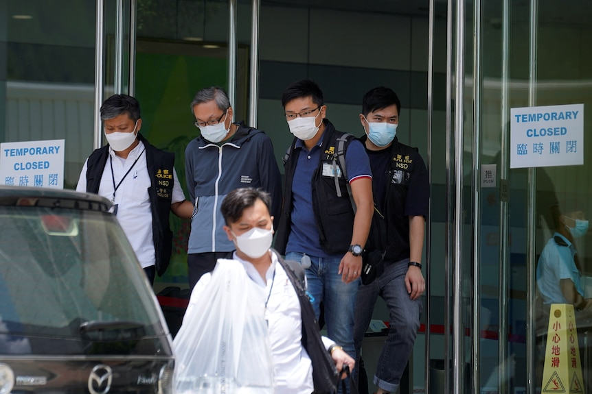 Police officers escort Apple Daily CEO Cheung Kim-hung from his offices on June 17.
