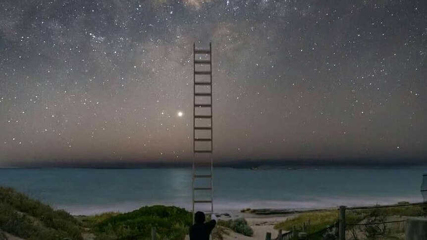 Man holds ladder up to starry sky