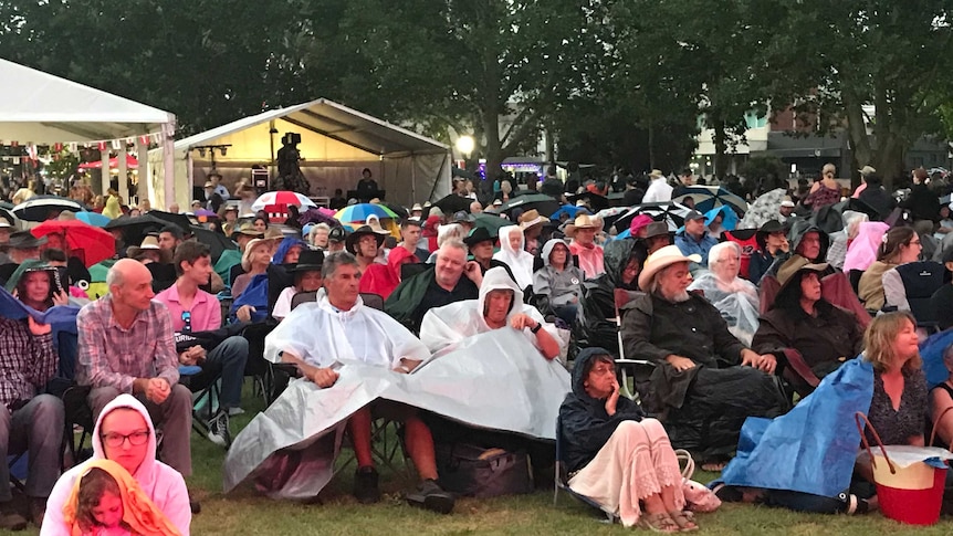 People sit in chair at an outdoor concert.