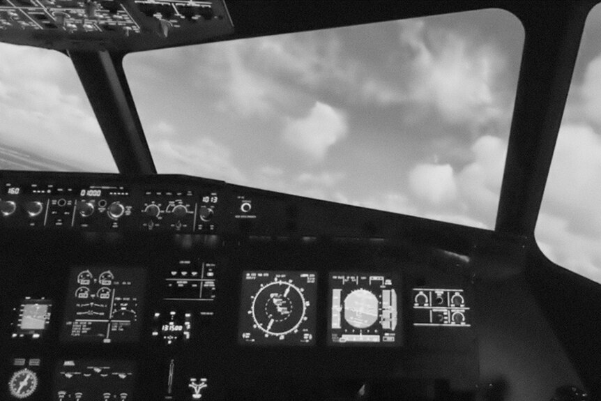 Black and white still of an airplace cockpit during a flight in 2019 documentary Present.Perfect.