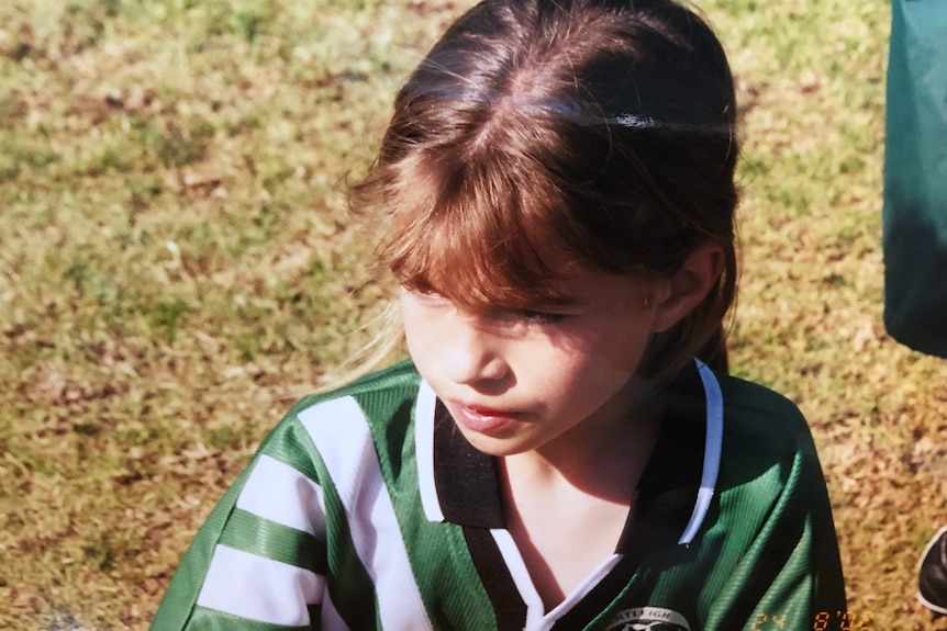 Steph Catley as a child in her green and white soccer gear.