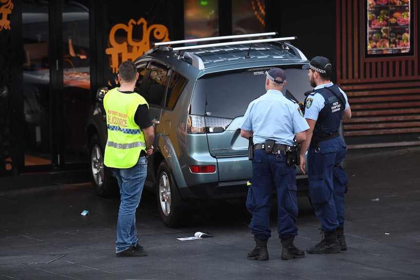 Police stand by the back of the car