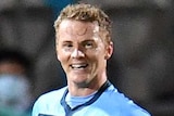 A Sydney FC A-League player smiles as he looks to his left at a teammate after he scored a goal against Wellington Phoenix.
