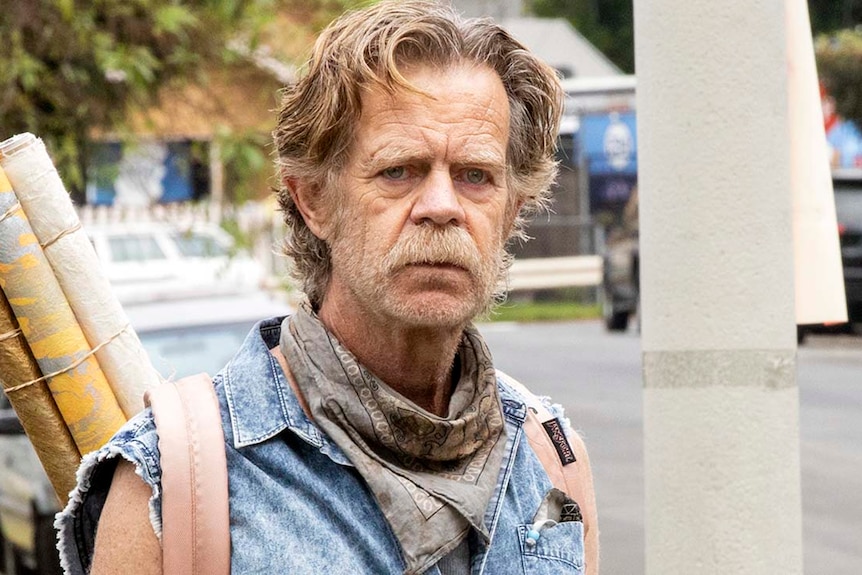 Frank Gallagher looks into the camera with a somber expression. 