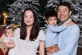 Man and woman pose with baby and toddler for Christmas photo with Santa