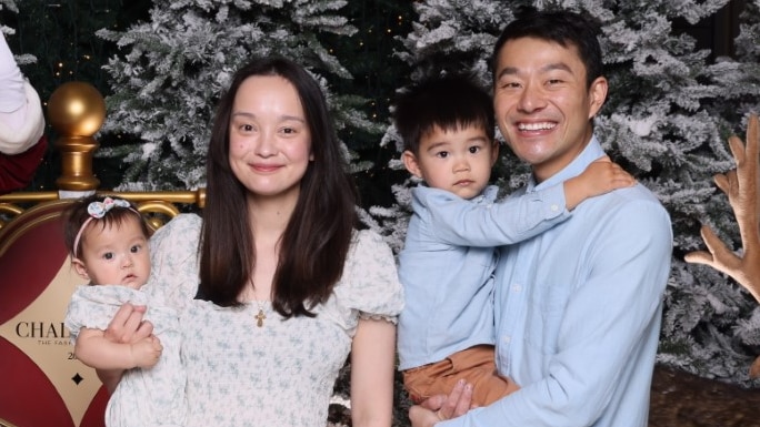 Man and woman pose with baby and toddler for Christmas photo with Santa