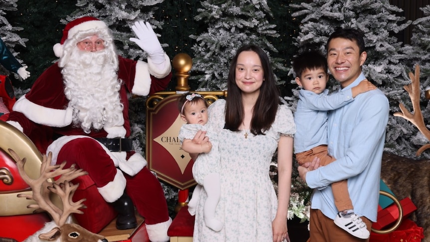 Man and woman pose with baby and toddler for Christmas photo with Santa