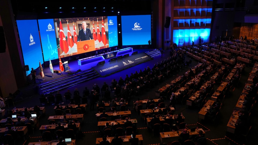 A shot from above of a large dark meeting hall.