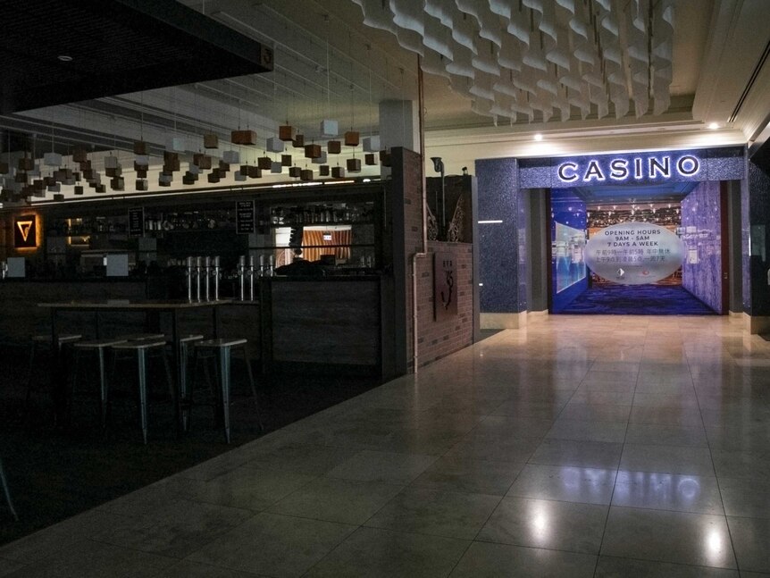 A cafe sits in darkness in front of the bright lights coming from the Casino gaming room doors