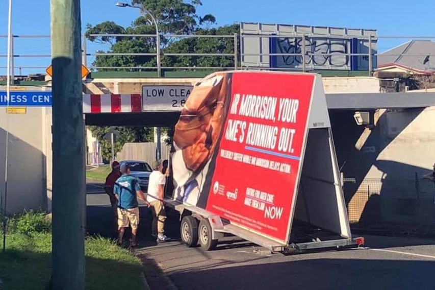Truck displaying political advertising stuck under bridge
