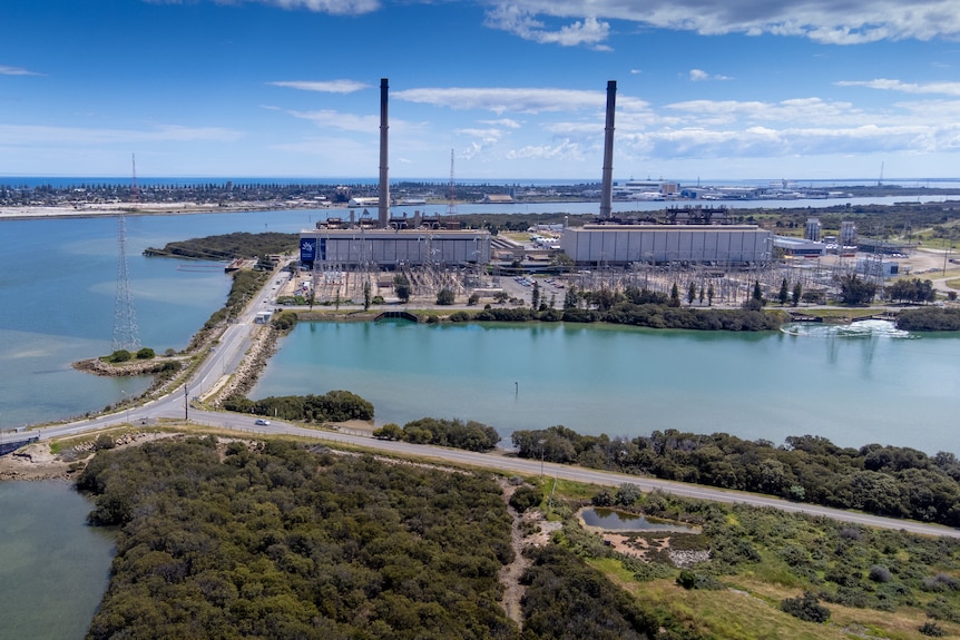 Two power stations with smoke stacks next to water with causeways to them