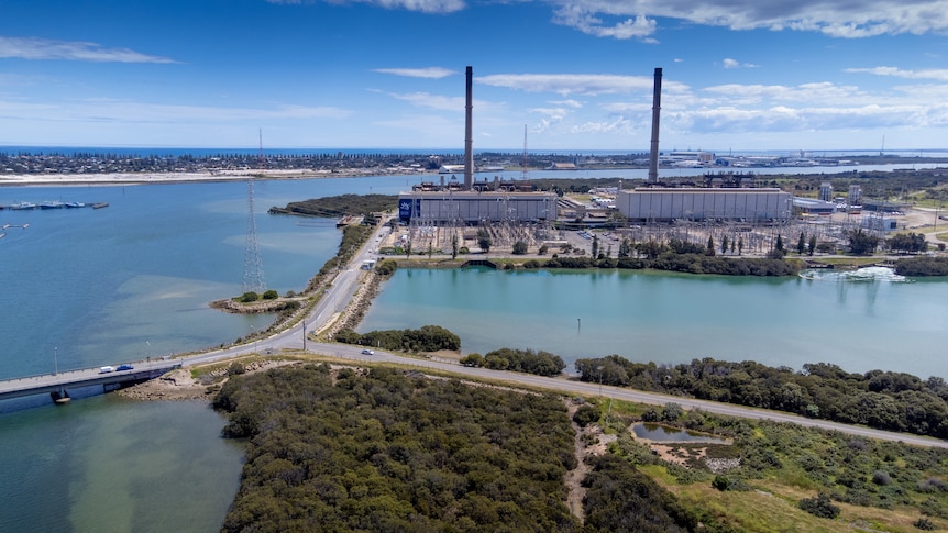 Two power stations with smoke stacks next to water with causeways to them