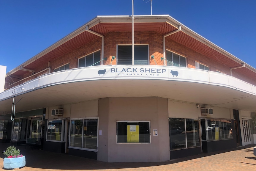 A row of empty shops on the corner of two streets in a country town.