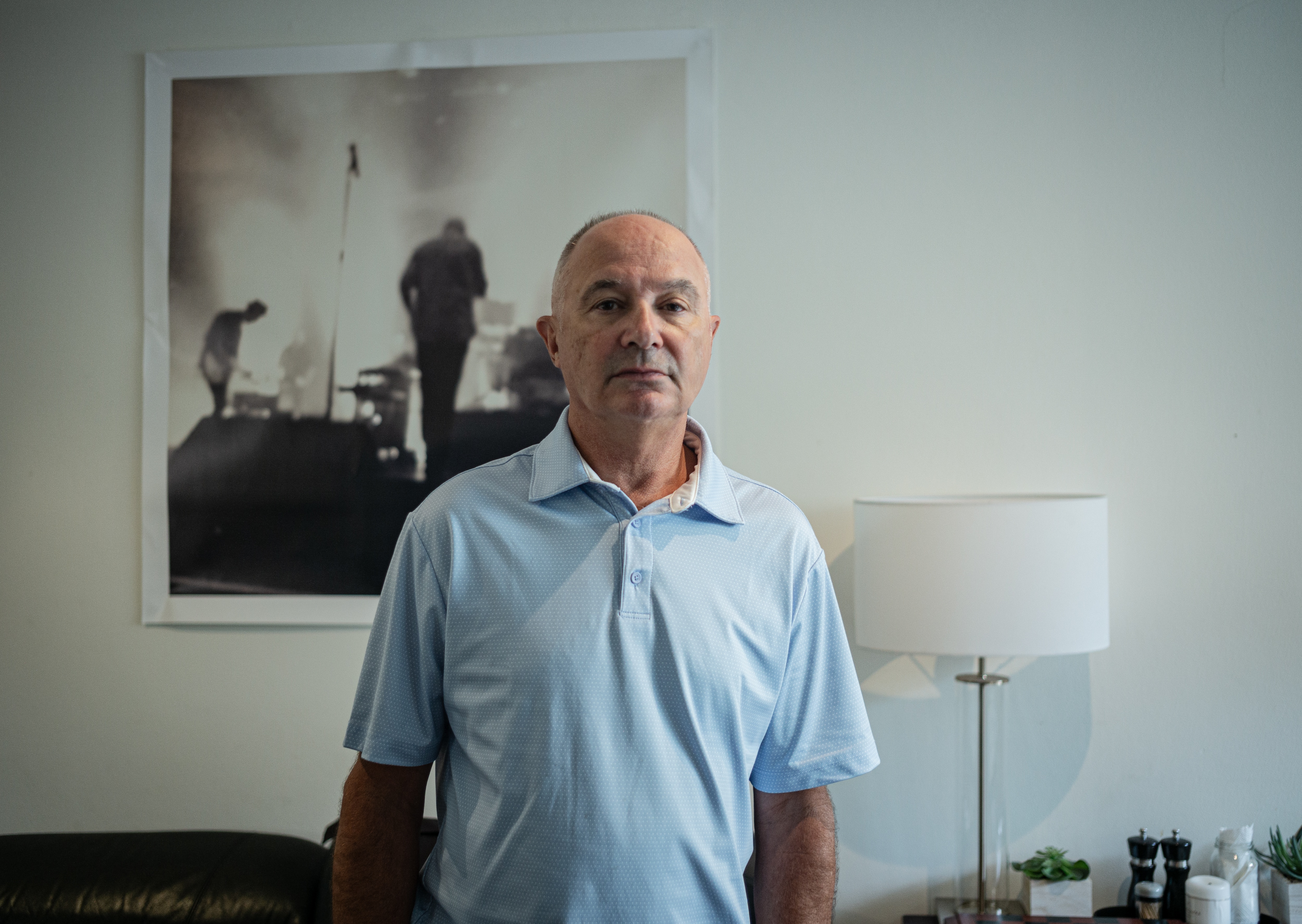 Tim Stannard stands in front of a lamp and picture in his loung room.