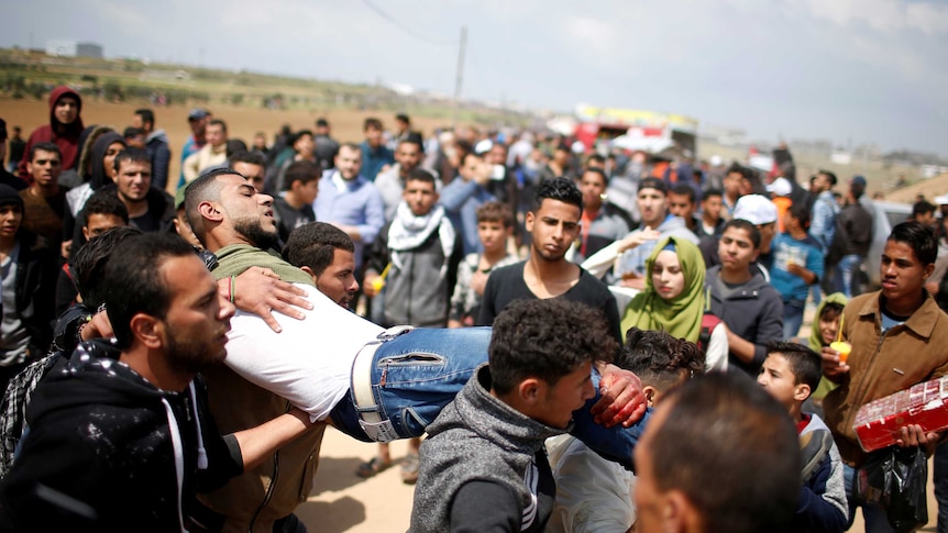 An injured man is carried by severall men at the site of the clashes near gaza