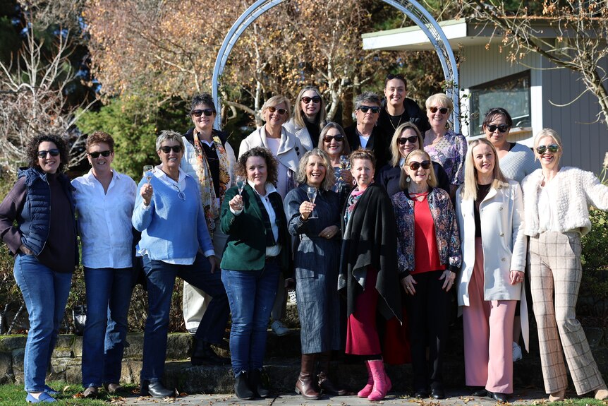 a large group of women outside holding glasses of wine