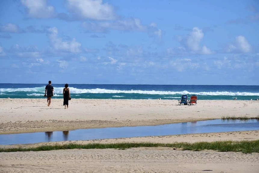 A couple walk towards the water at Cylinder Beach on North Stradbroke Island.