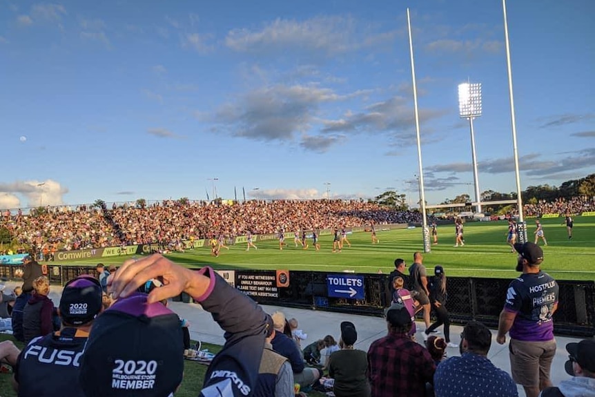 Lots of people in a crowd watching an NRL game