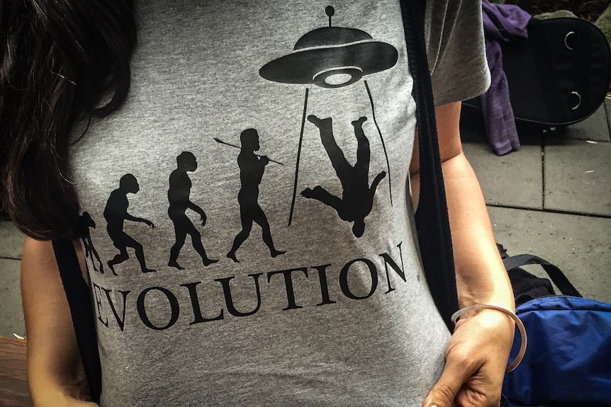 Woman in T-shirt with picture of human being lifted up by UFO