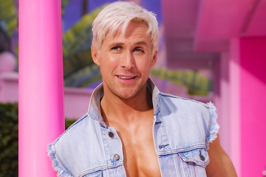 Ryan Gosling as Ken with bleached blonde hair and a denim shirt showcasing his abs