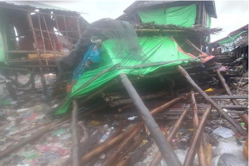 Buildings on stilts wrapped in green tarpaulins sit collapsed across long timber stilts.