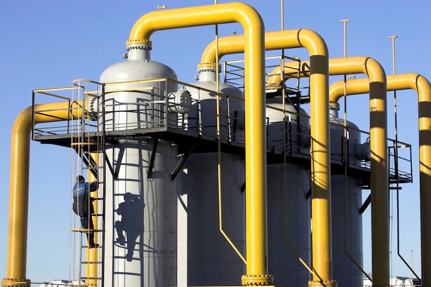 A worker climbs a cylinder at a gas compressor station