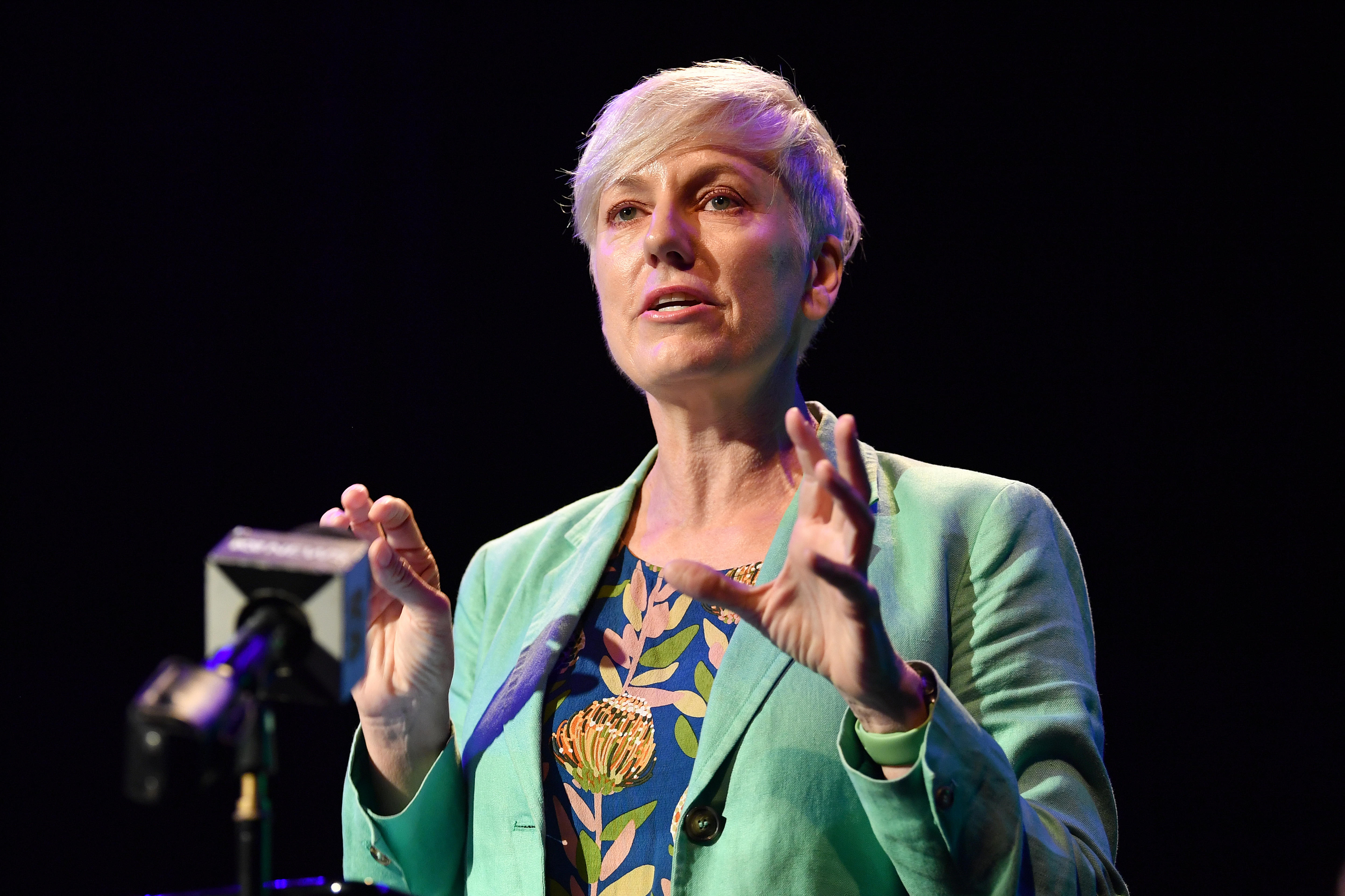 A woman with short blonde hair wearing a green jacket