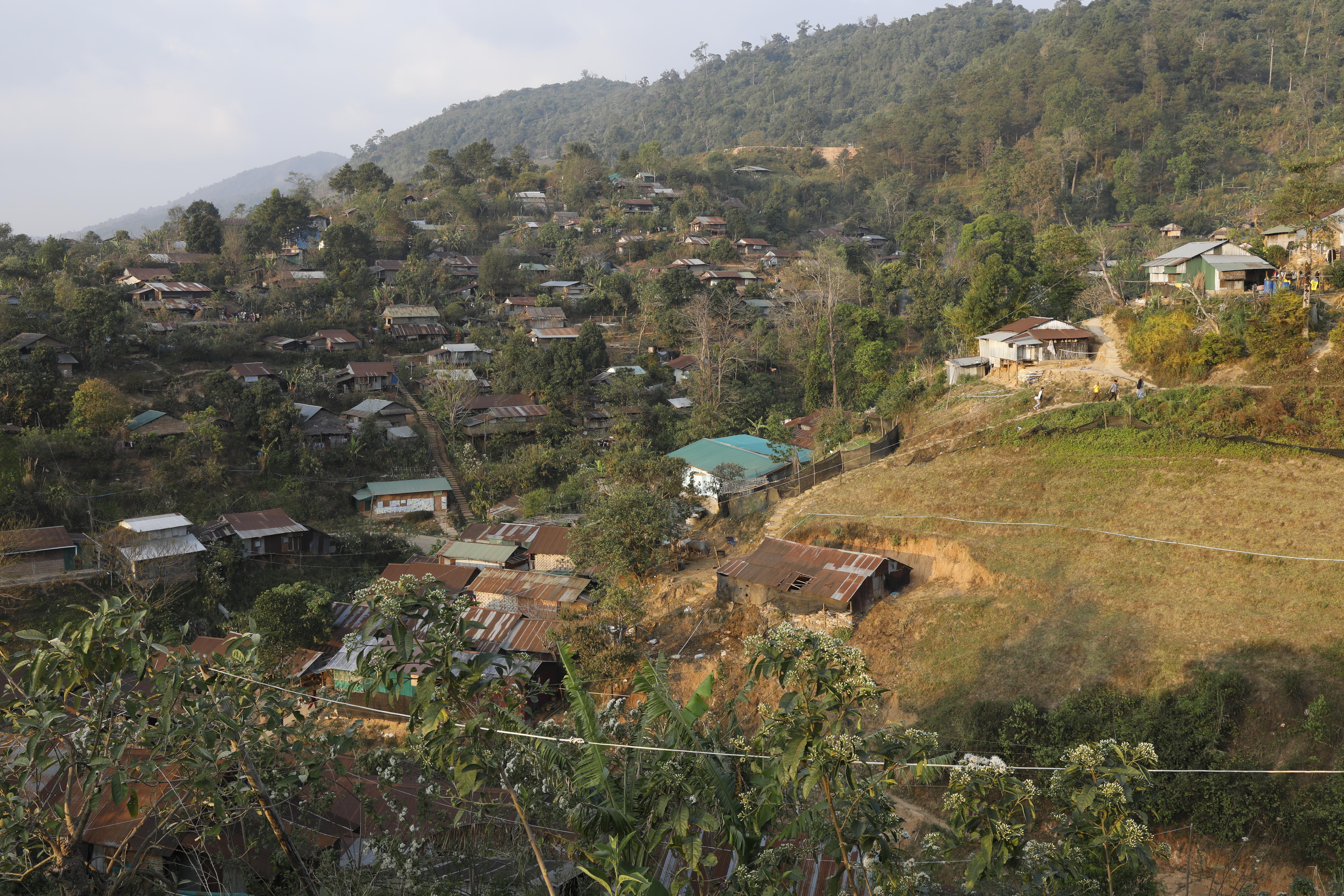 Houses, many with rusted corrugated iron sheet roofing, are dotted through a verdant mountain valley.