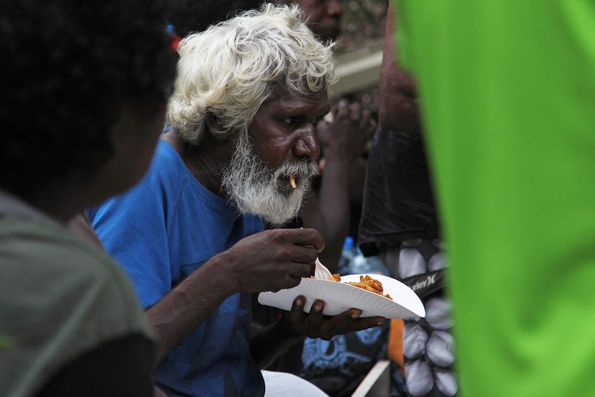 A photo of an Indigenous man eating a plate of food.