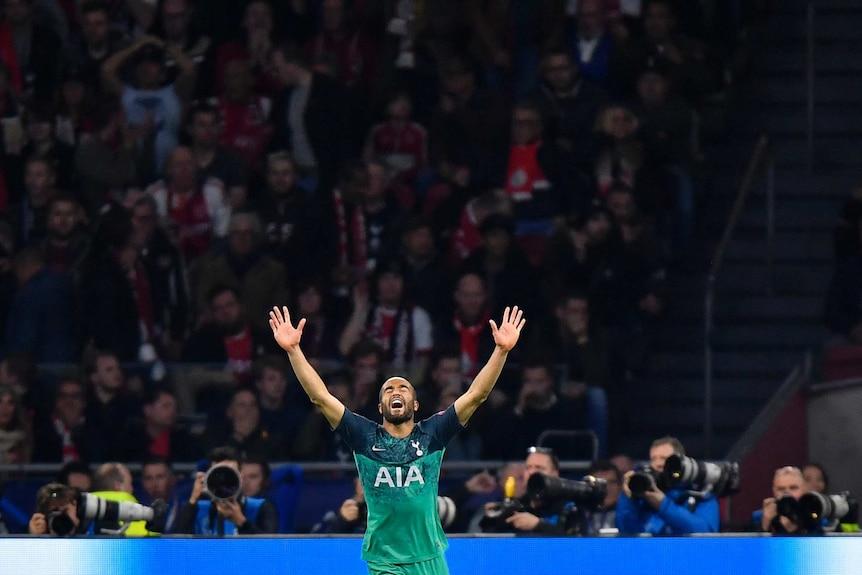A footballer raises his arms to the air as he celebrates a goal