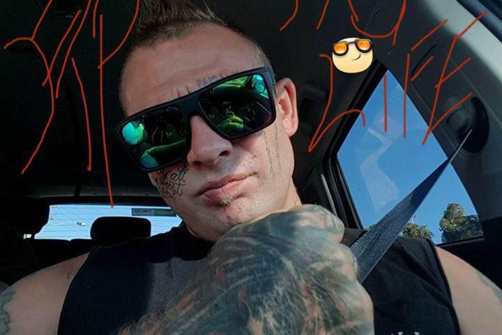 A heavily tattooed man wearing sunglasses is pictured sitting in a car.