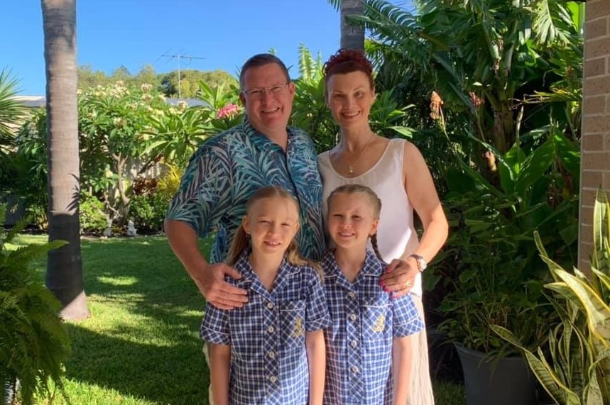 Marcus Carter stands with his wife and twin daughters in school uniforms.