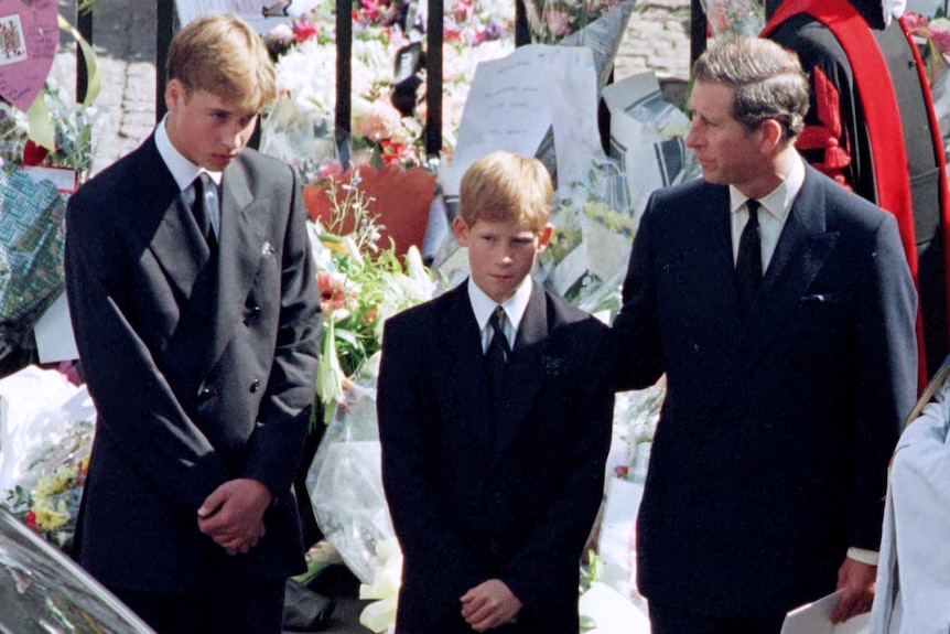 Prince Charles touches the shoulder of his son Harry as his other son Prince William.