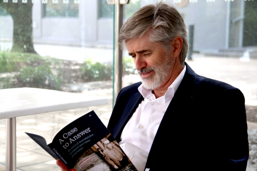 A man sits down reading a book.